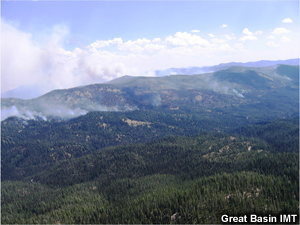 Fire burns the upper portions of a rolling hillscape.